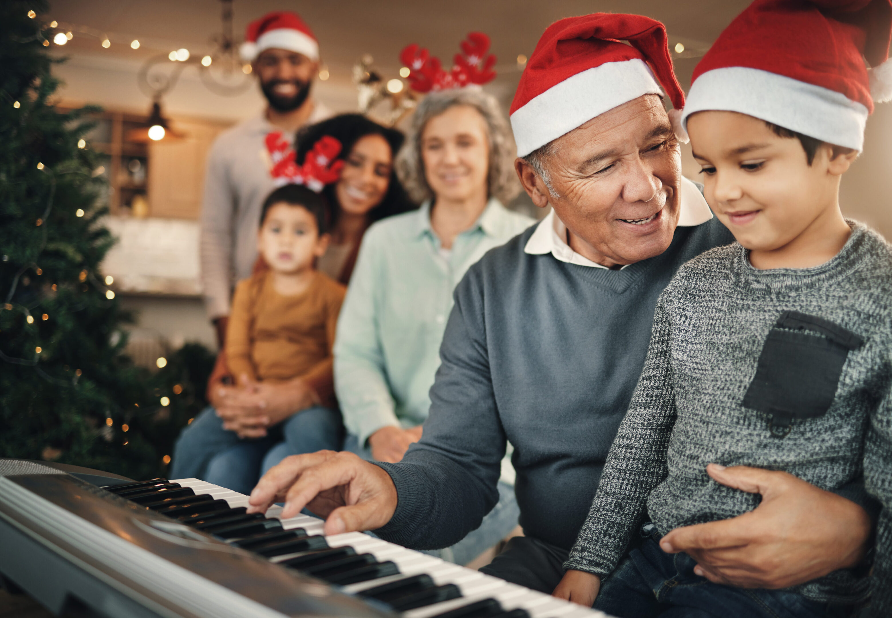 Family, christmas and senior man with grandchild on piano for learning, teaching and bond in their home. Music, instrument and retired pianist performing for kids and parents in festive celebration